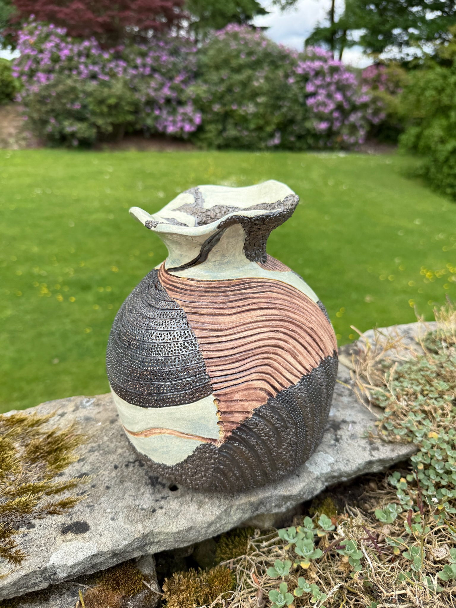 Wheel-thrown textured pot on a garden stone