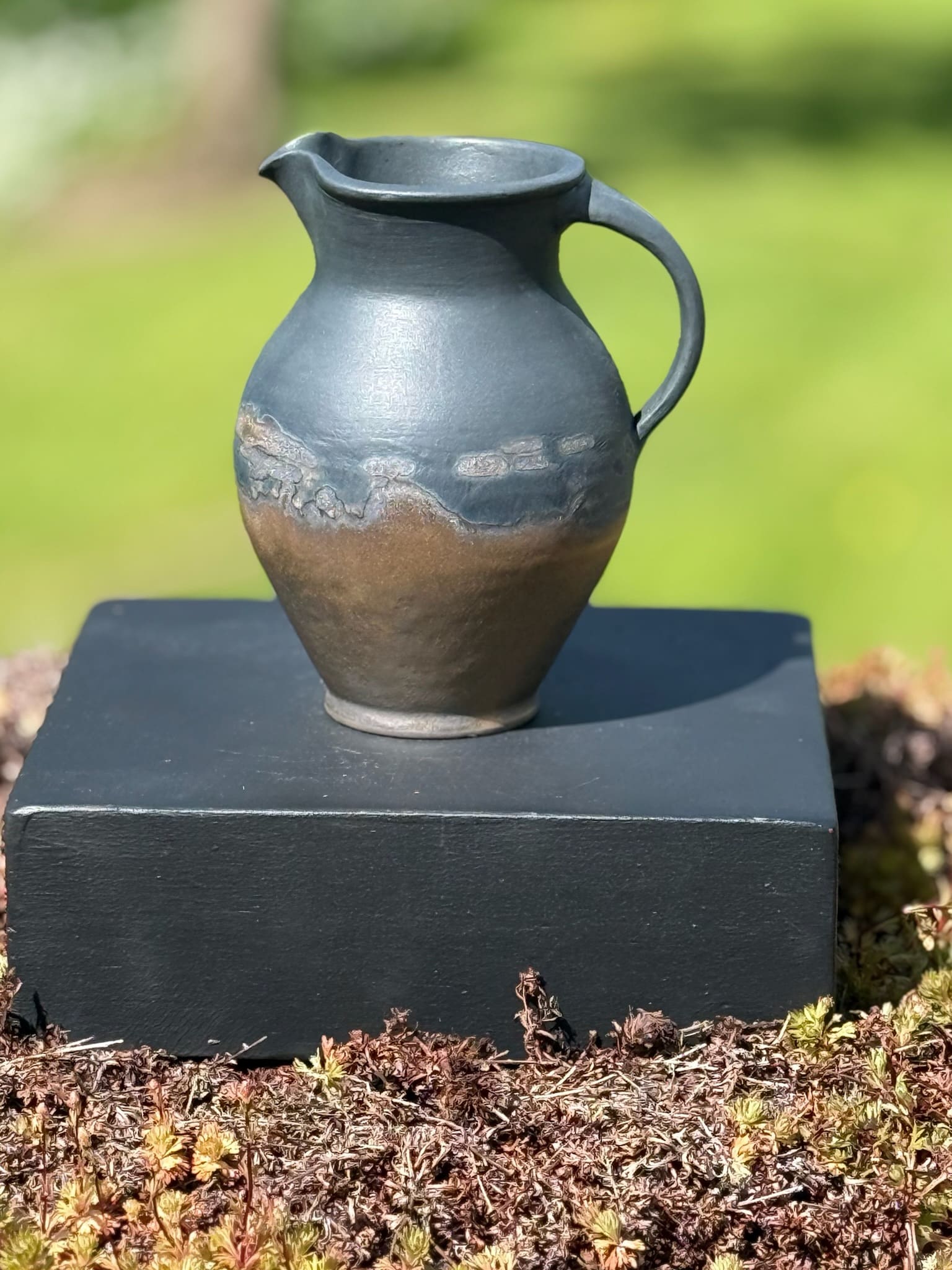 Bronze and black curved jug with handle