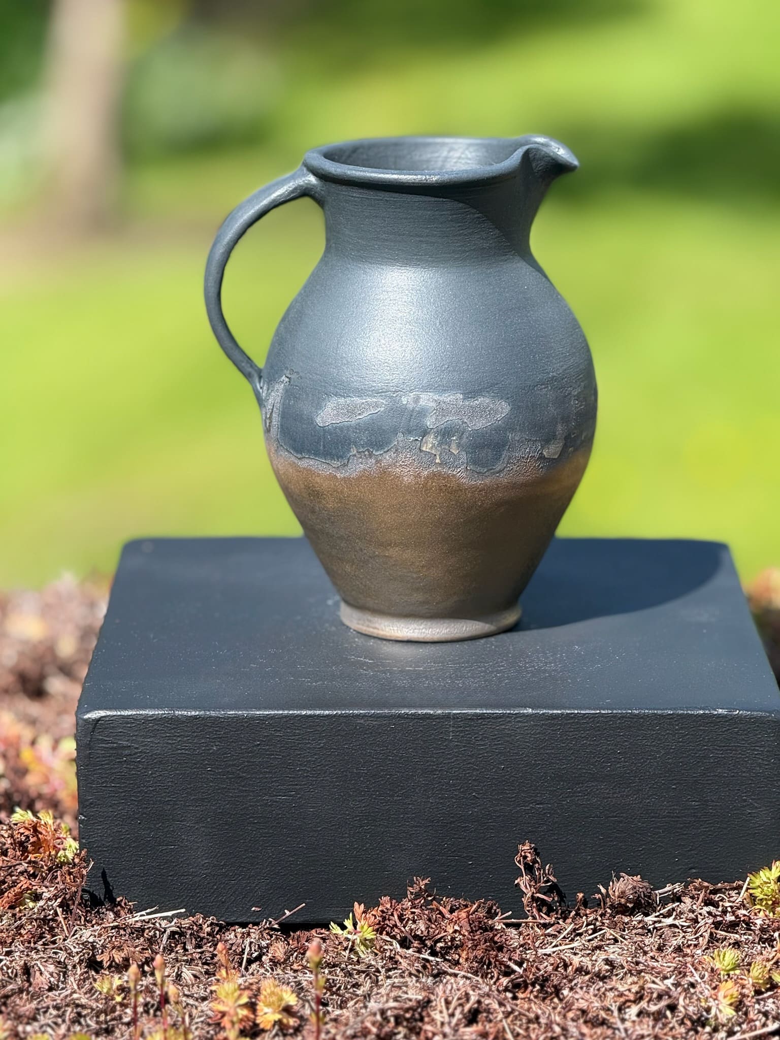 Bronze and black curved jug, profile view