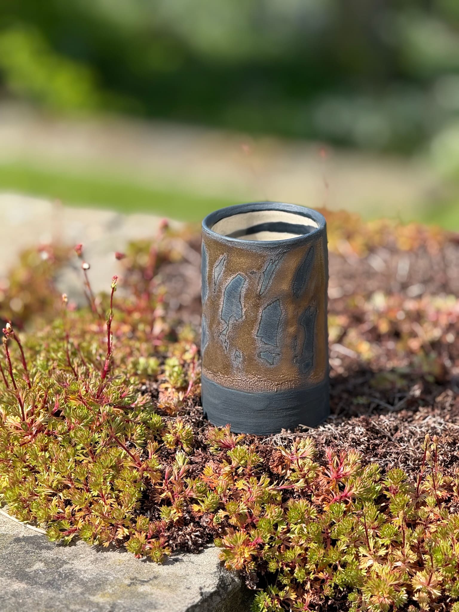 Bronze and black tall cylindrical container