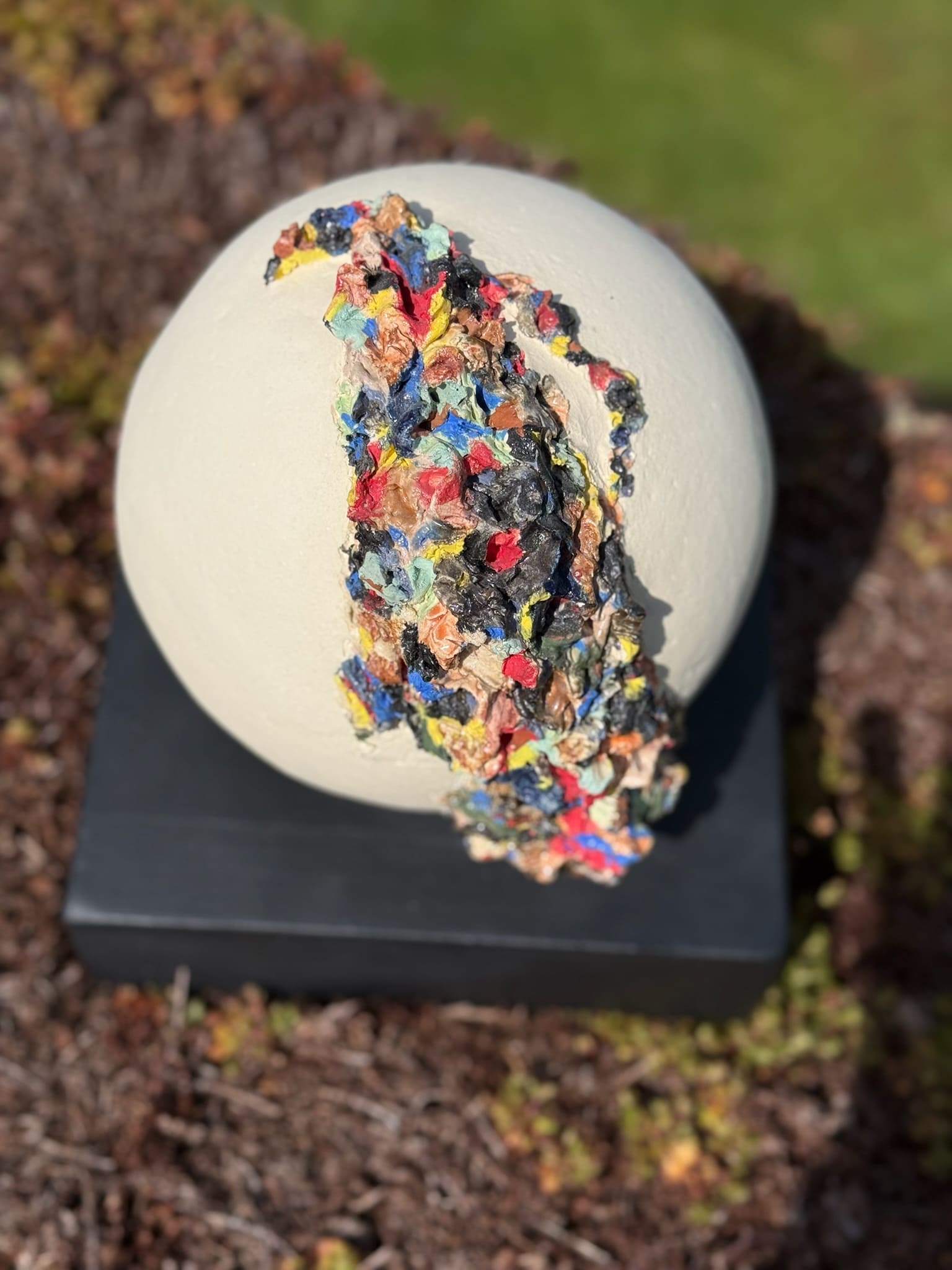 White ceramic sphere with circular opening revealing layered colour inside