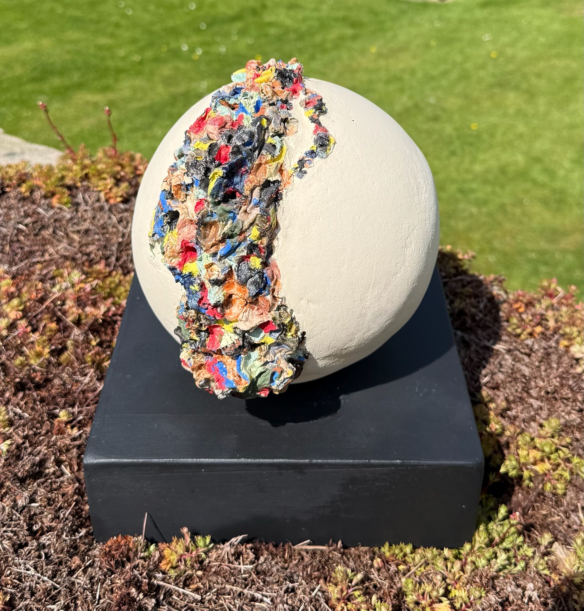 White ceramic sphere with a round aperture revealing vivid colour within