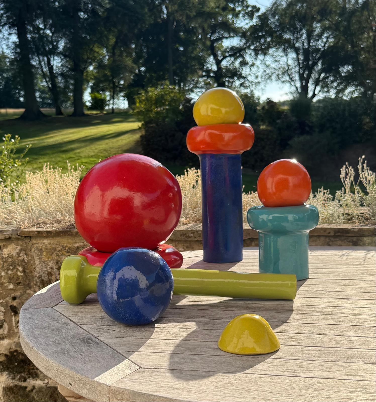 Brightly glazed ceramic forms on a stone pathway, viewed from above in dappled light