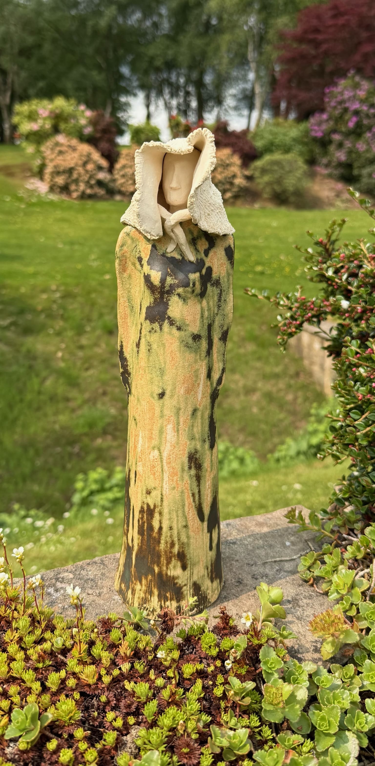 Hooded ceramic figure with veiled face, mottled green glaze