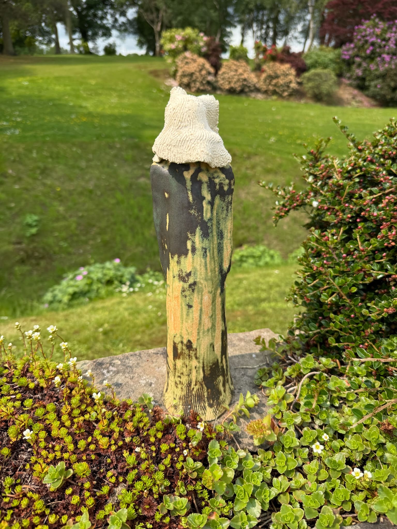 Standing hooded ceramic figure, mottled ochre and green glaze